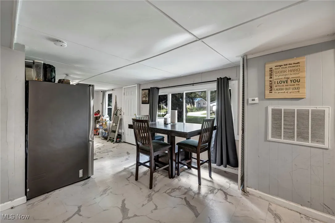 Dining space with wooden walls and light marble finish floors