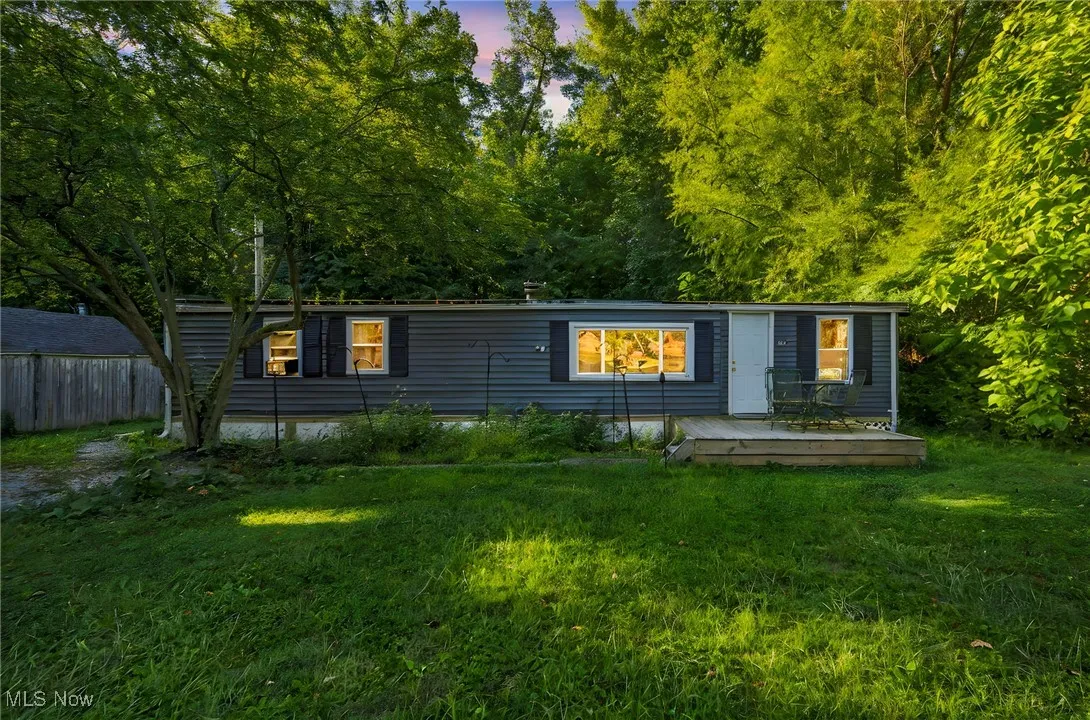 View of front of property with a yard, a deck, and view of wooded​​‌​​​​‌​​‌‌​‌‌​​​‌‌​‌​‌​‌​​​‌​​ area