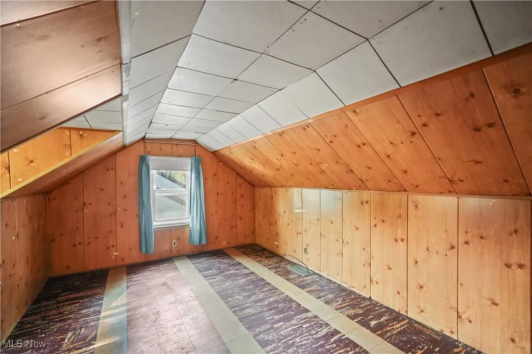 Additional living space featuring wood walls and vaulted ceiling