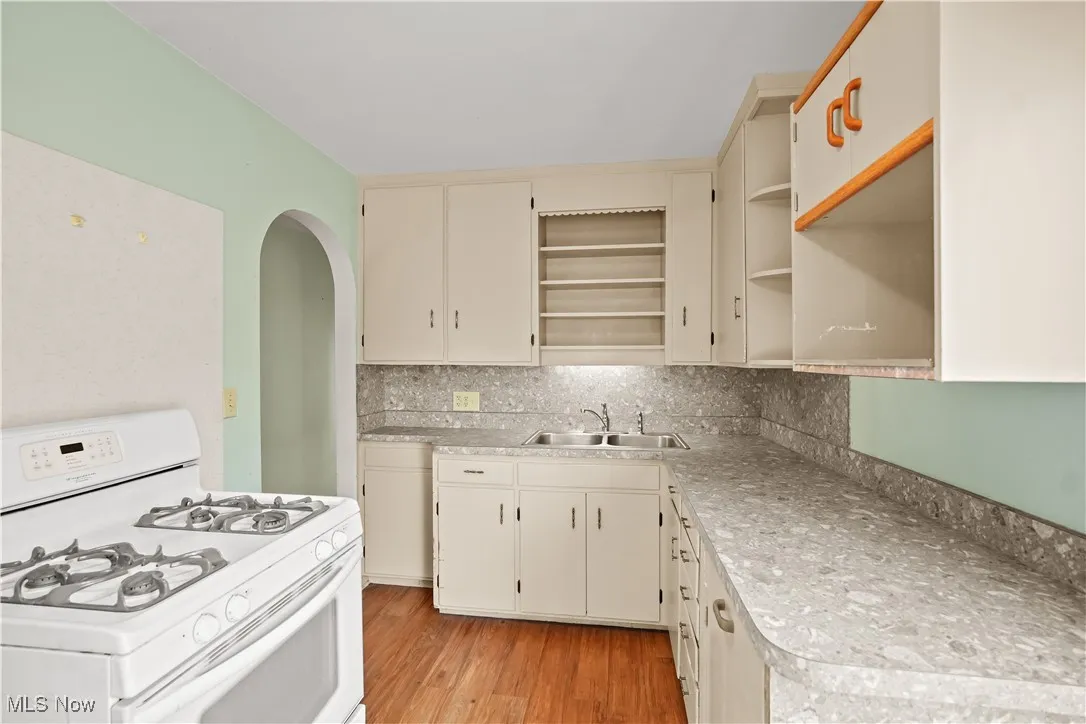 Kitchen with gas range gas stove, tasteful backsplash, open shelves, and light countertops