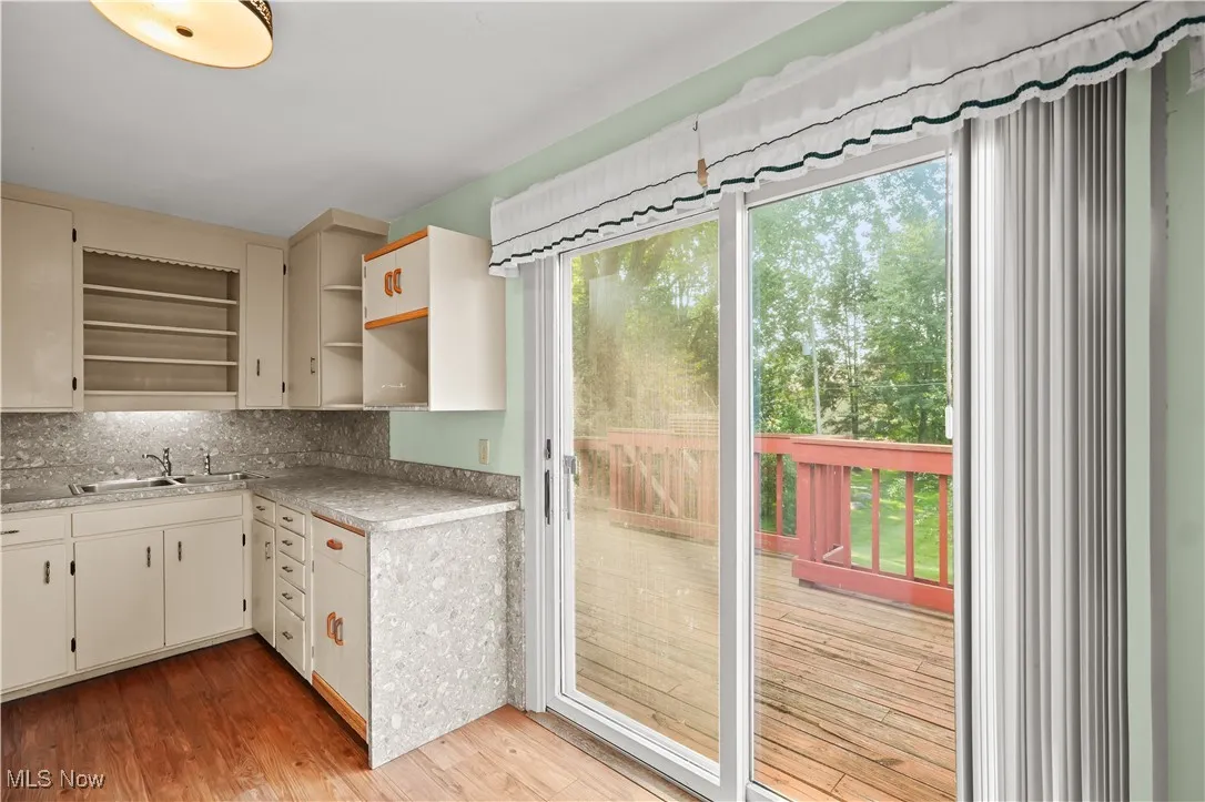 Kitchen featuring cream cabinetry, light countertops, light wood-style floors, and tasteful backsplash