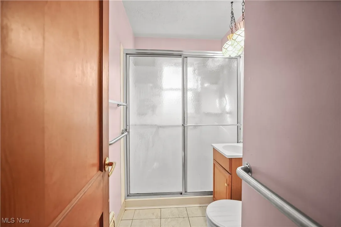 Bathroom featuring vanity, light tile patterned floors, and a stall shower