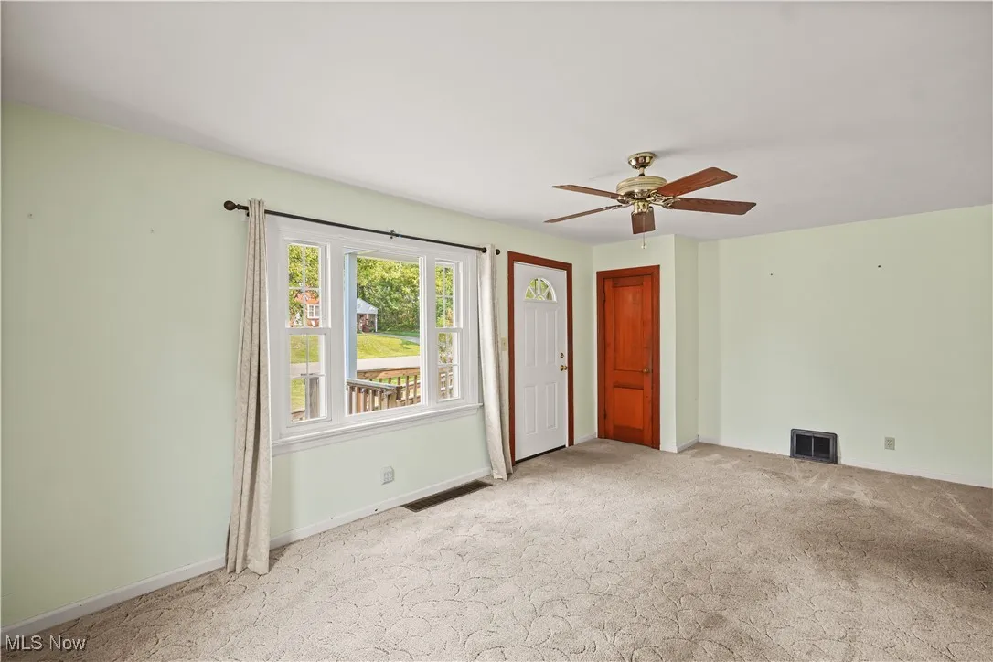 Empty room with light carpet and ceiling fan