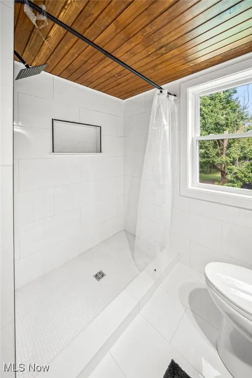 Bathroom featuring a stall shower, wooden ceiling, tile patterned floors, and tile walls