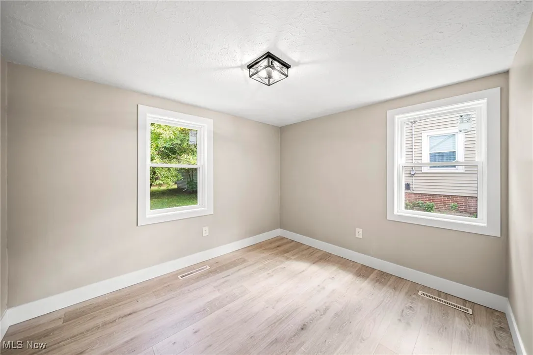 Empty room featuring healthy amount of natural light, light wood-style flooring, and a textured ceiling