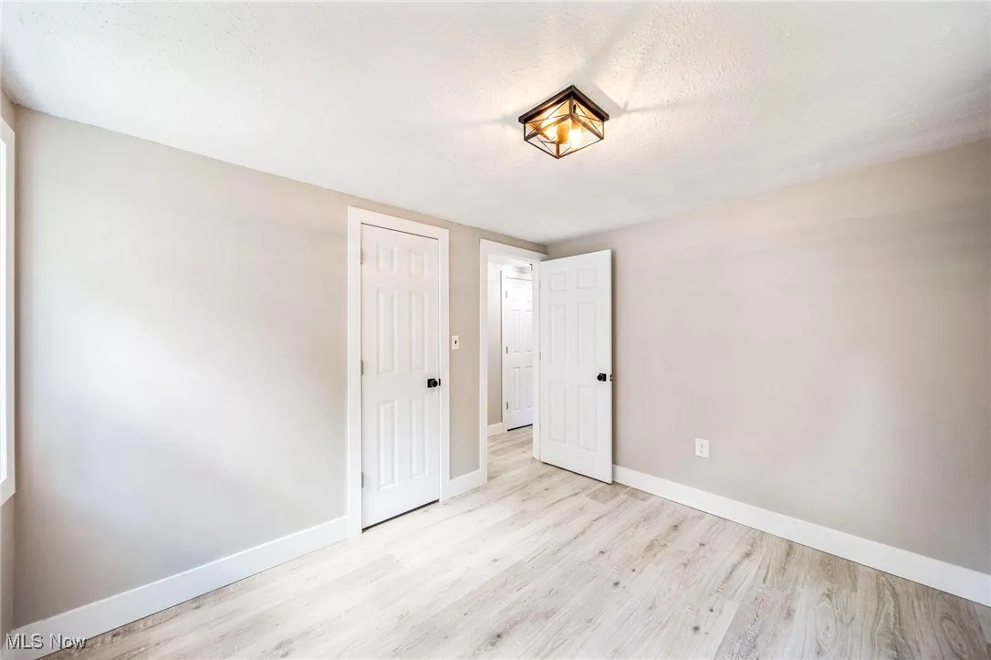 Unfurnished bedroom with a closet, light wood-style flooring, and a textured ceiling