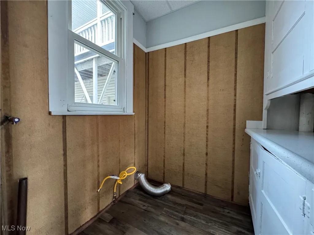 Laundry room featuring dark wood-style floors and cabinet space