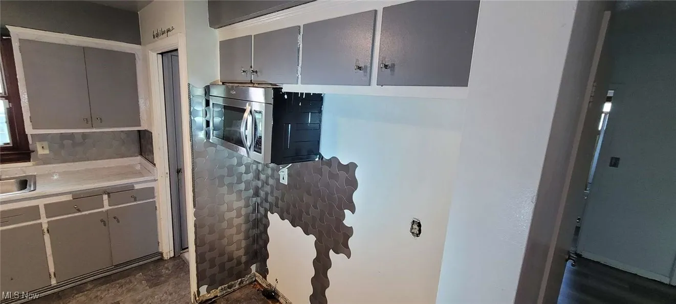 Kitchen with light countertops, gray cabinets, and stainless steel microwave