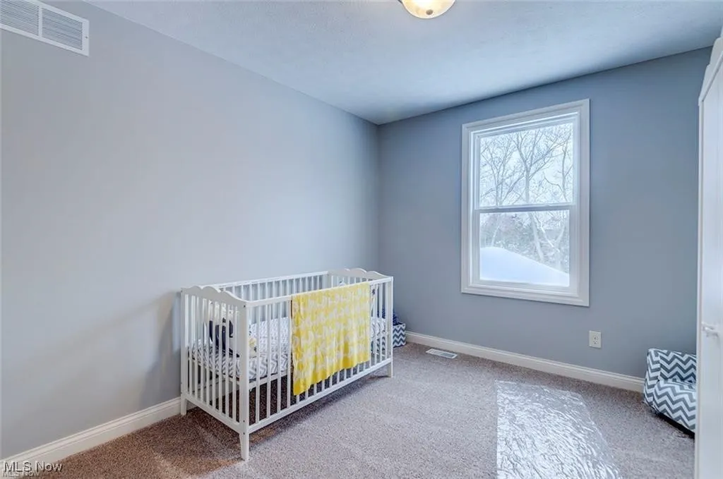 Bedroom featuring carpet and a crib