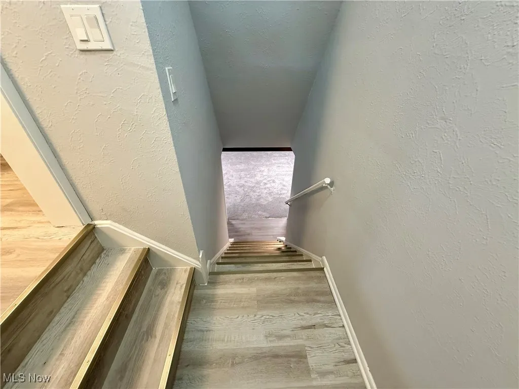 Stairway with a textured wall and wood finished floors