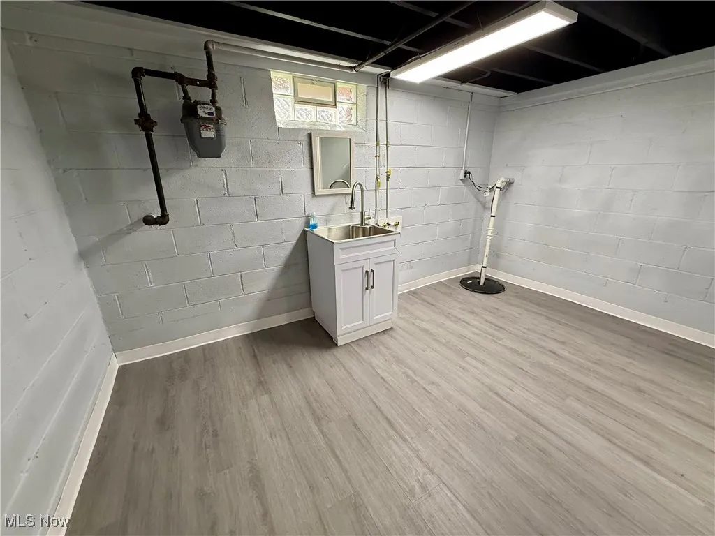 Basement with light wood-style flooring and drainage system
