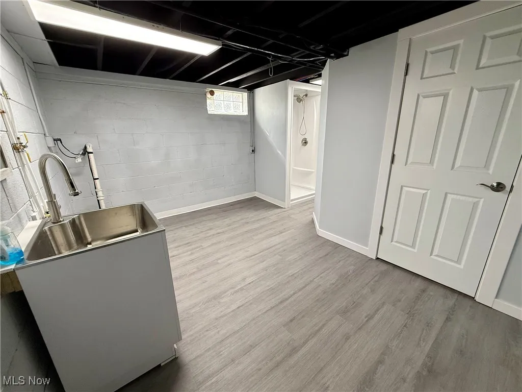 Below grade area with light wood-style floors and baseboards
