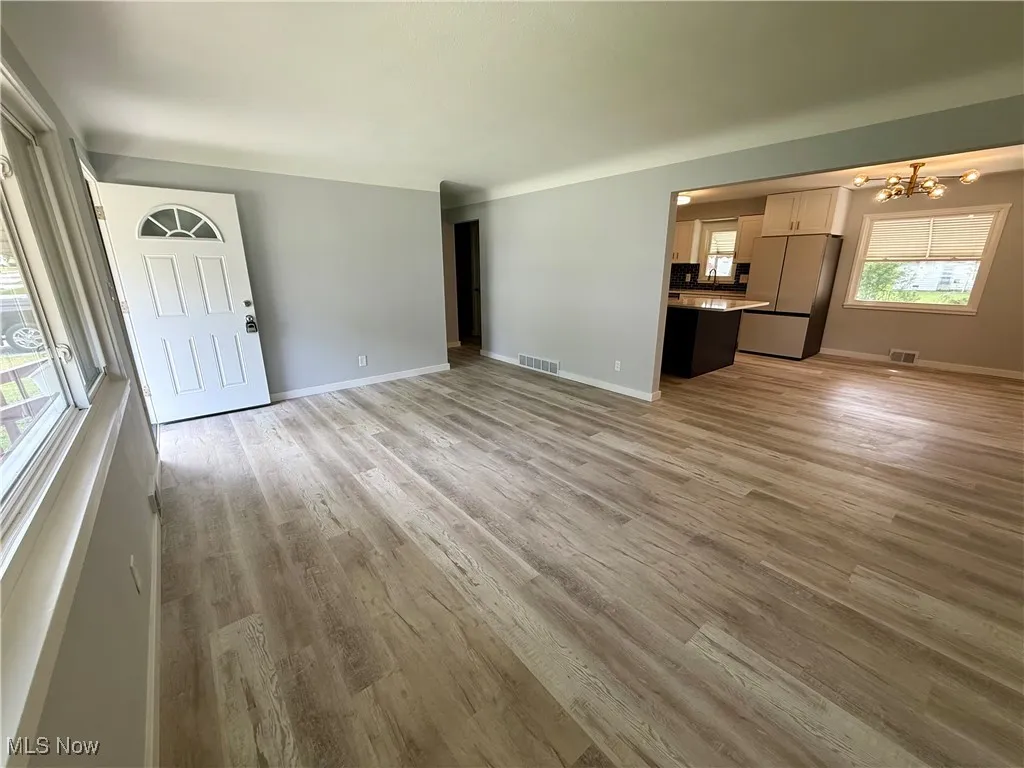 Unfurnished living room featuring light wood finished floors and a chandelier