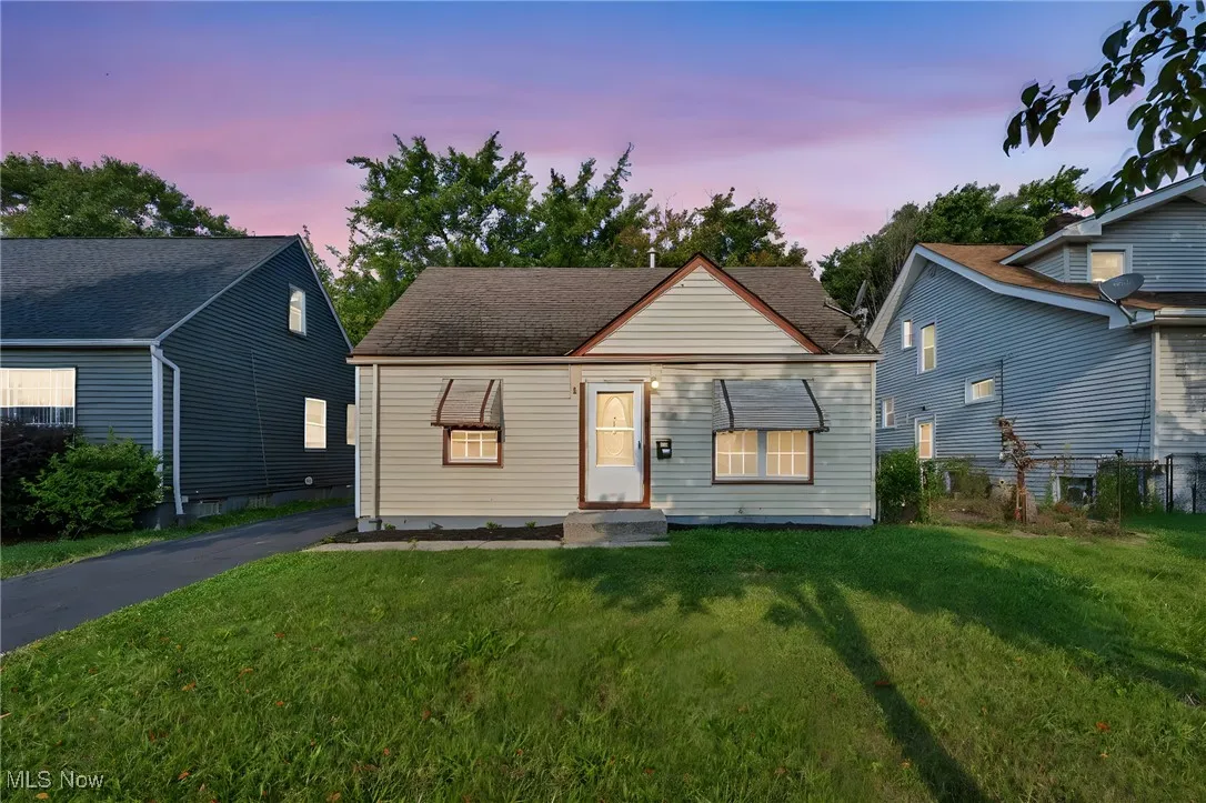 Bungalow-style home with a lawn and roof with shingles