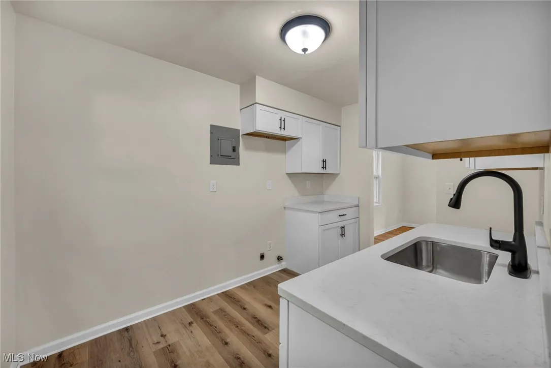 Kitchen featuring white cabinets, light wood-type flooring, and electric panel