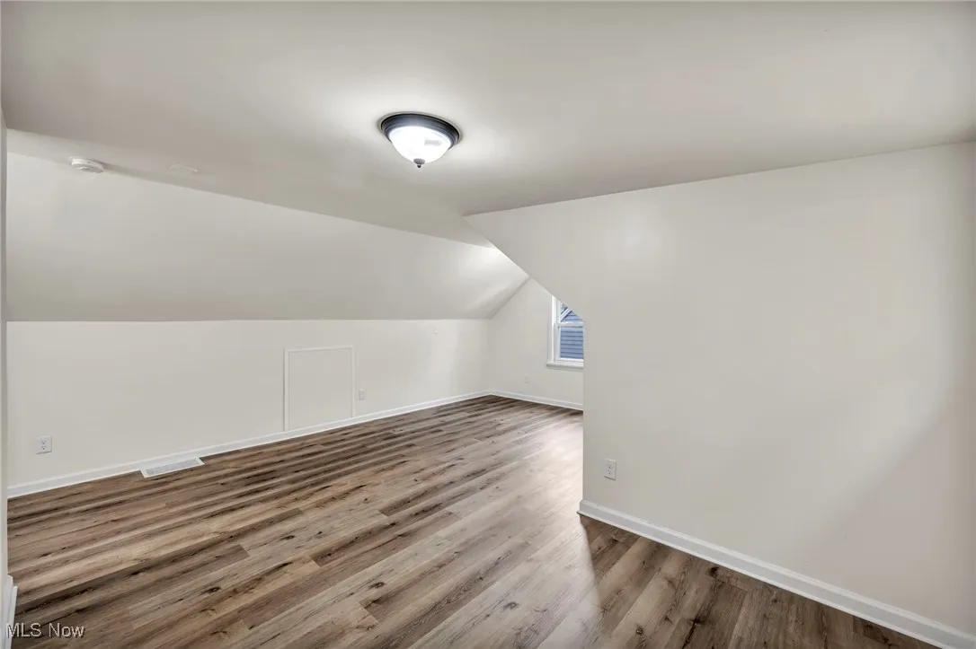Attic bedroom featuring light wood finished floors, plenty of natural light, and vaulted ceiling