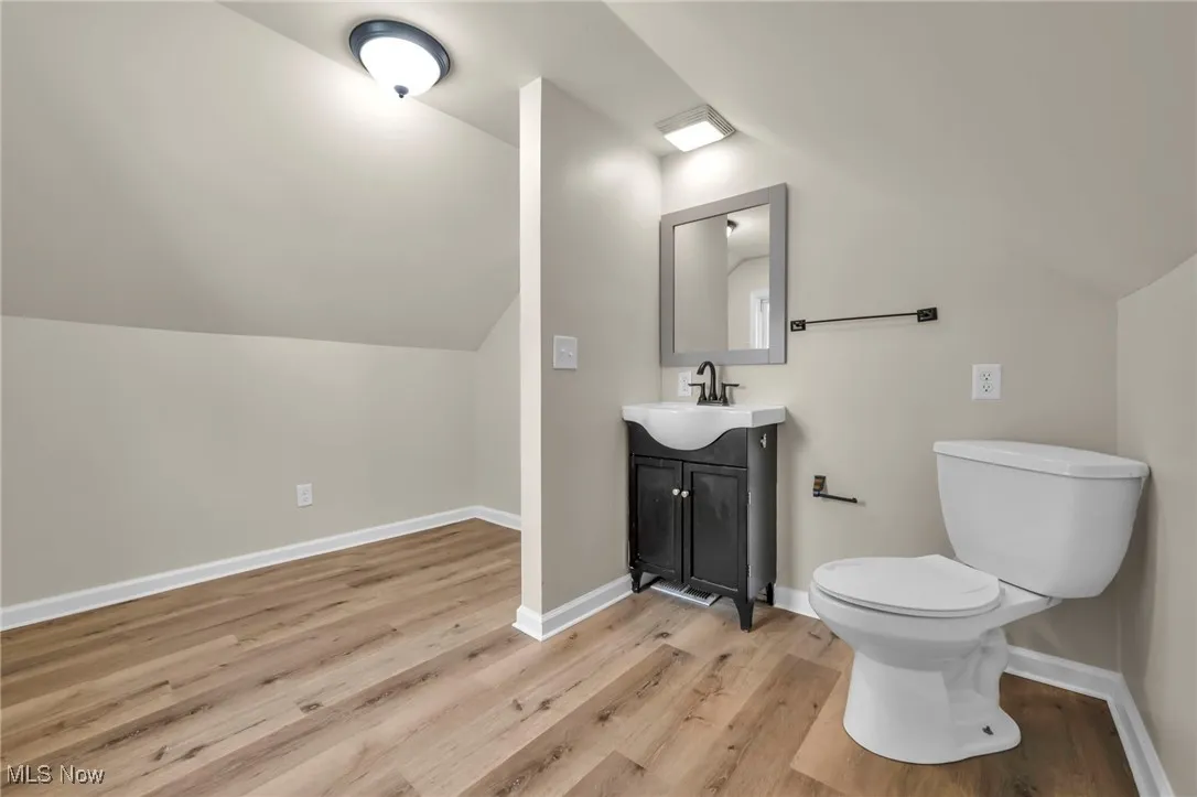 Attic bedroom Bathroom with lofted ceiling, vanity, and light wood finished floors