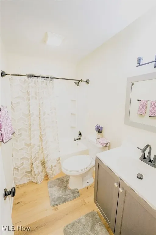 Full bath with light wood finished floors, vanity, and shower / bath combo