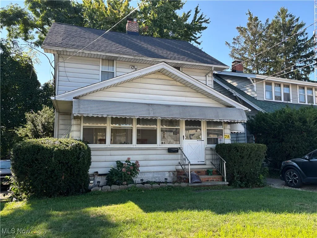 View of front facade featuring a chimney, a front lawn, and a shingled roof