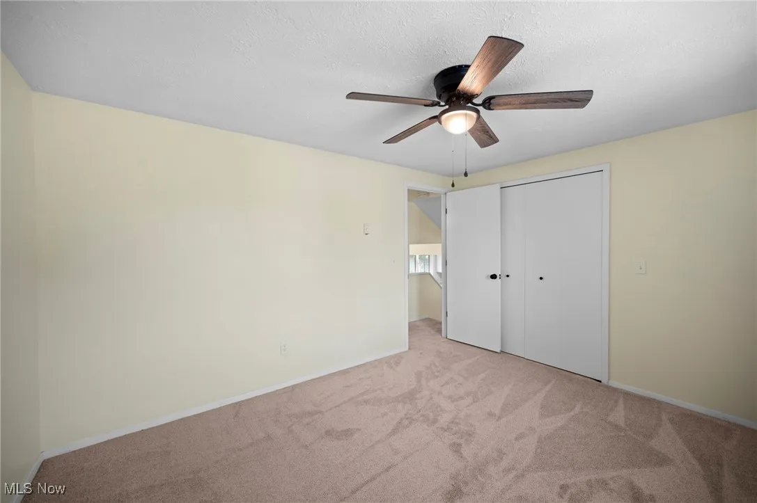 Unfurnished bedroom featuring carpet, a closet, ceiling fan, and a textured ceiling