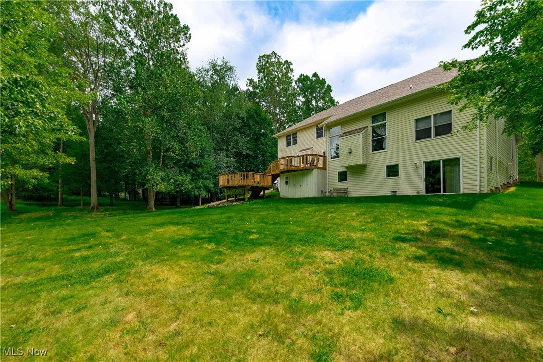 View of green lawn with a deck and view of scattered trees