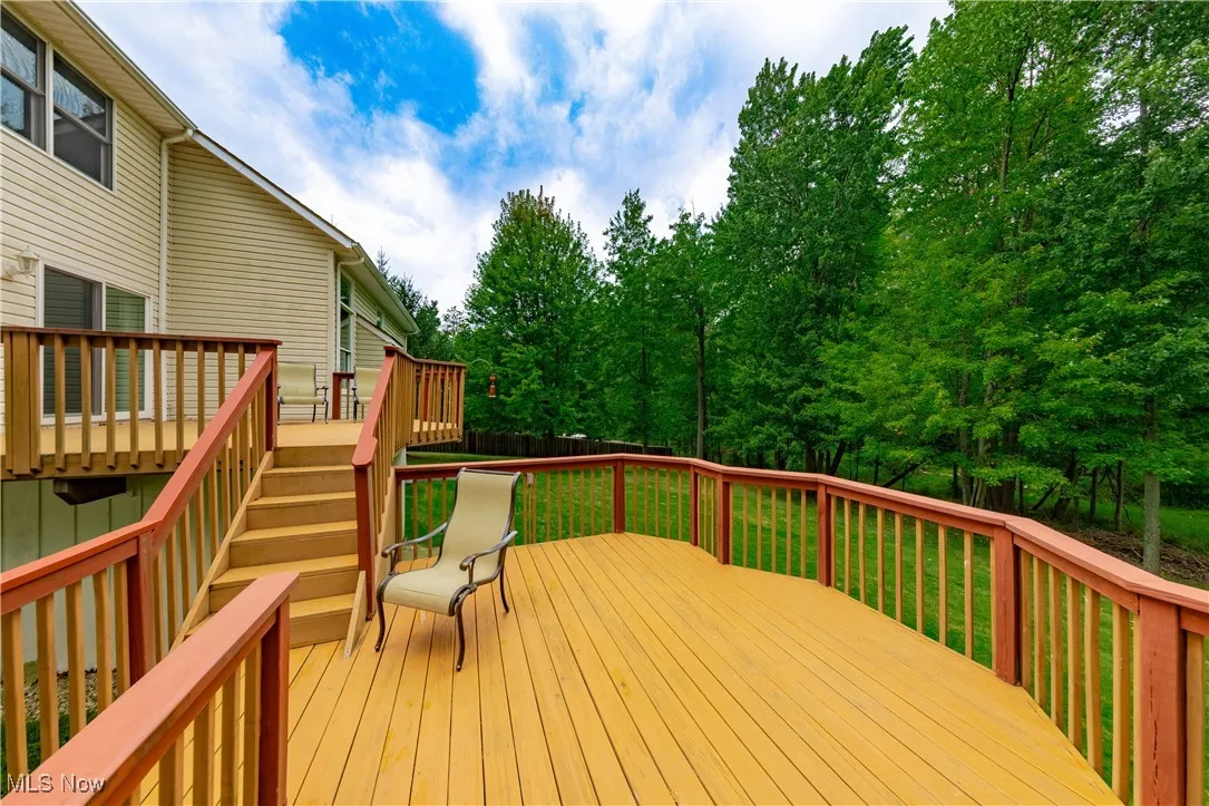 Wooden terrace featuring stairway and view of wooded area
