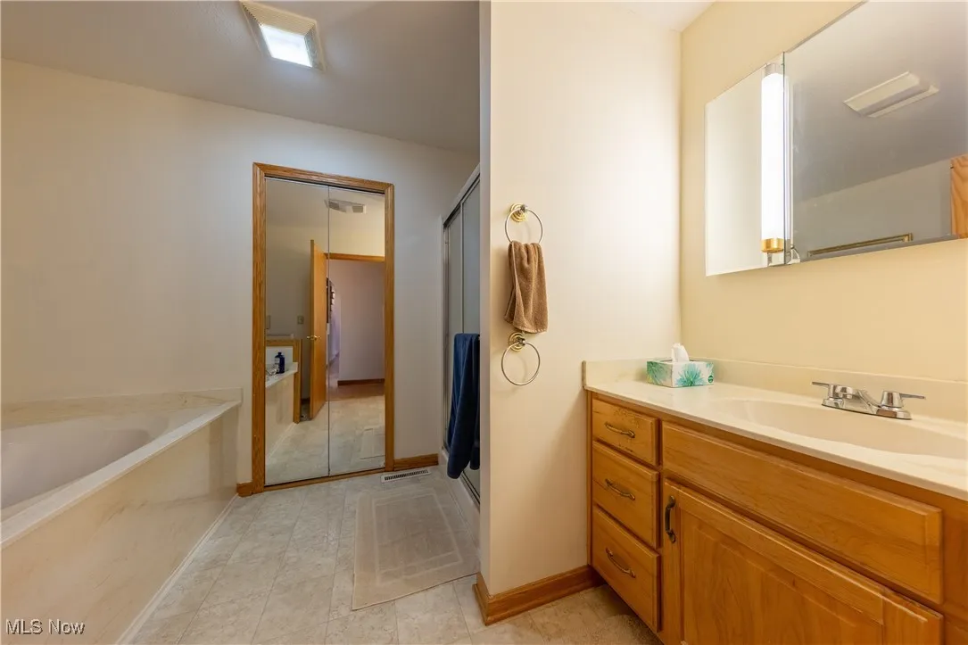 Full bathroom with vanity, a bath, a stall shower, and light tile patterned floors