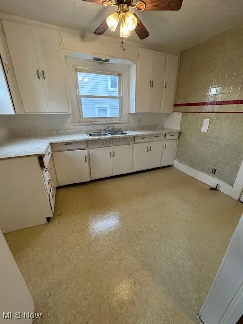 Kitchen featuring white cabinetry, light countertops, a ceiling fan, and light flooring