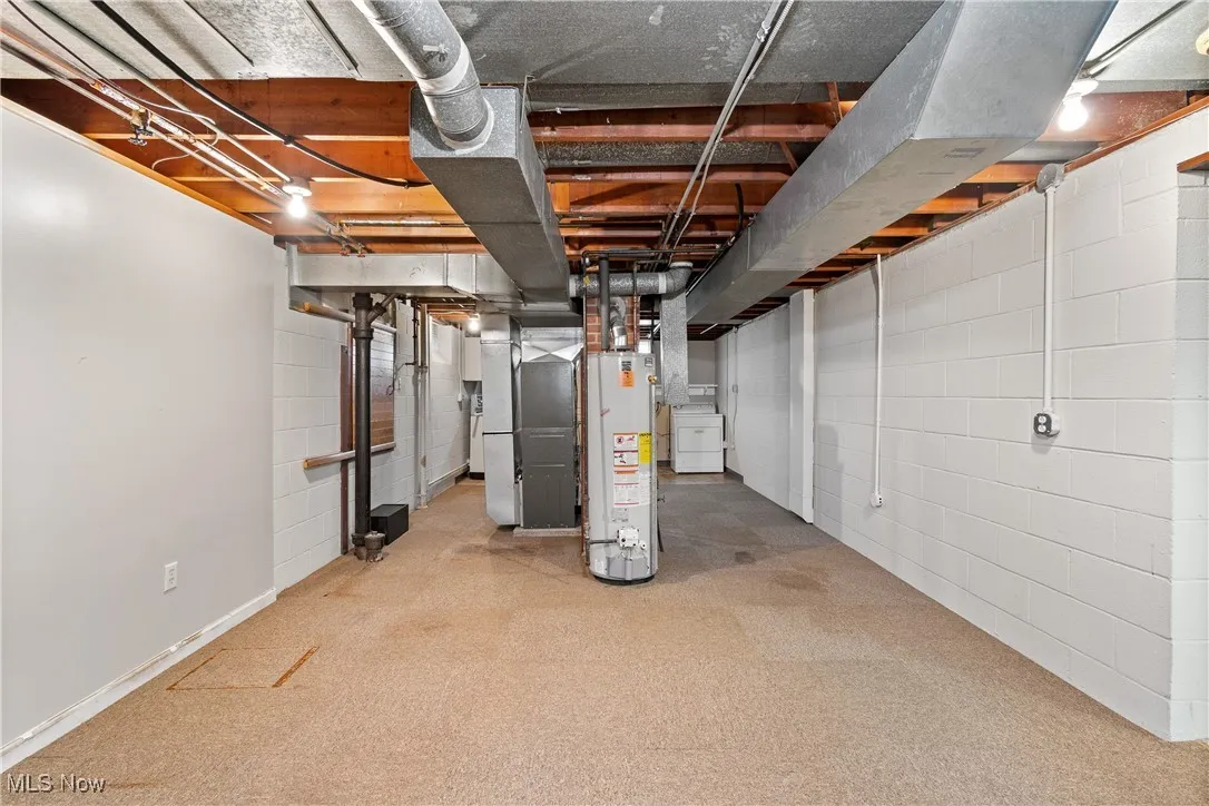 Unfinished basement with washer / dryer, heating unit, water heater, and light colored carpet