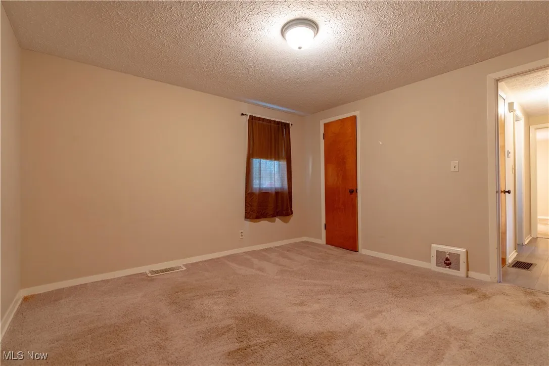 Unfurnished bedroom featuring light colored carpet and a textured ceiling