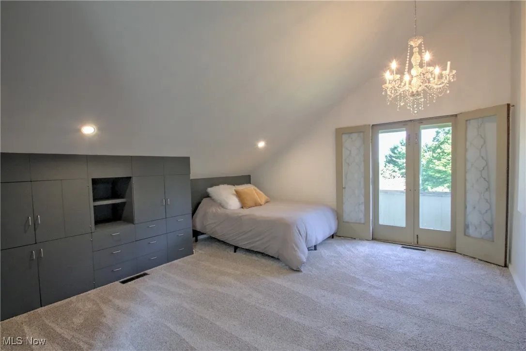 Bedroom featuring lofted ceiling, carpet floors, access to exterior, a chandelier, and french doors