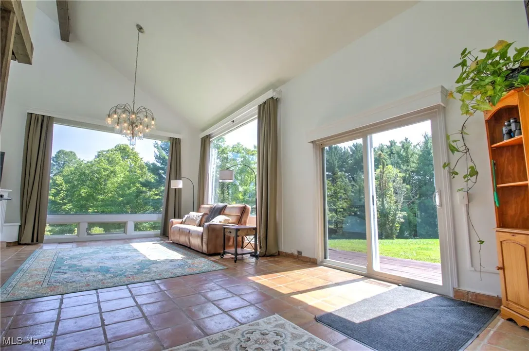 Doorway to outside with a chandelier, healthy amount of natural light, and high vaulted ceiling
