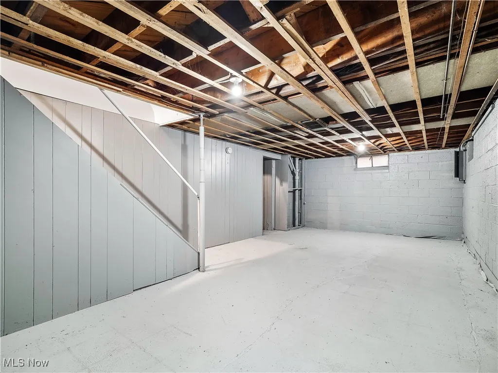 Basement featuring stairs, heating unit, and electric panel
