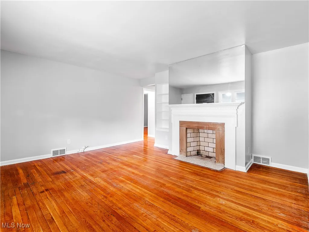 Unfurnished living room with light wood-style floors, a fireplace, and built in features