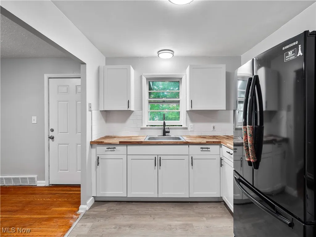 Kitchen featuring freestanding refrigerator, wooden counters, white cabinetry, and light wood finished floors
