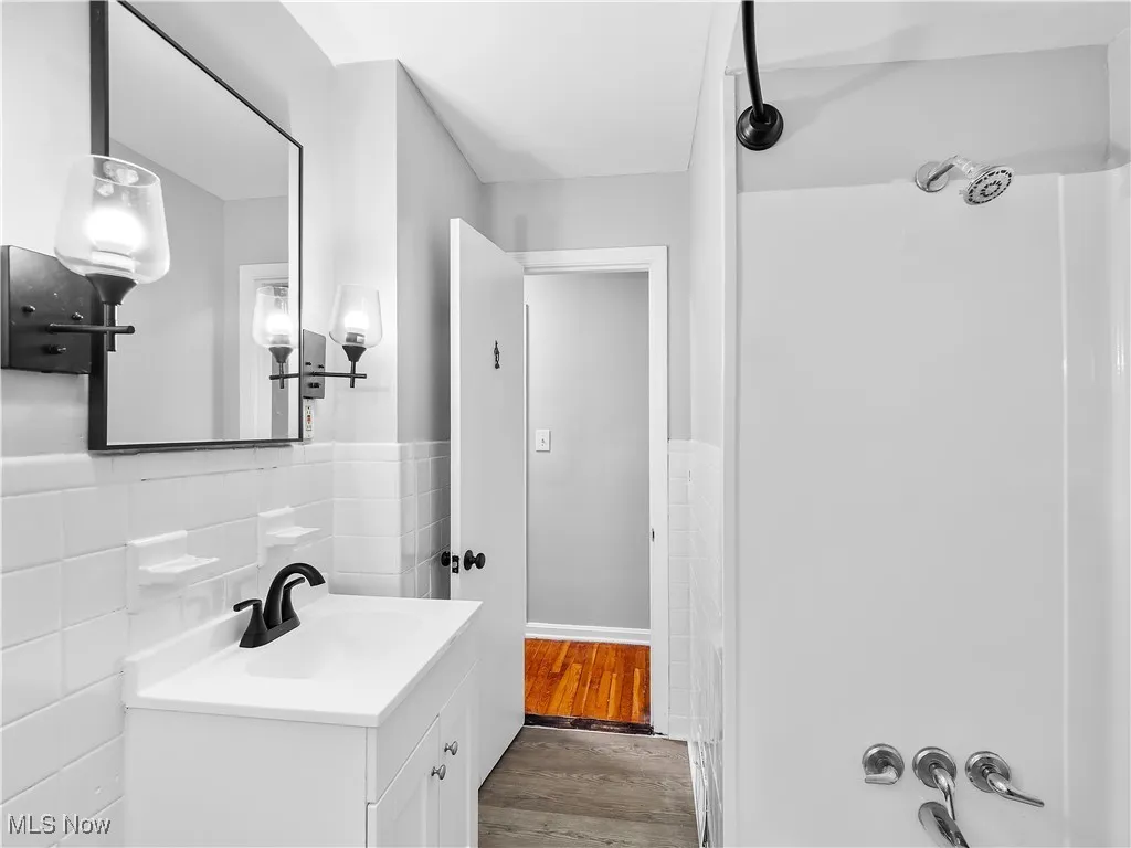Bathroom with tile walls, vanity, wood finished floors, and a wainscoted wall