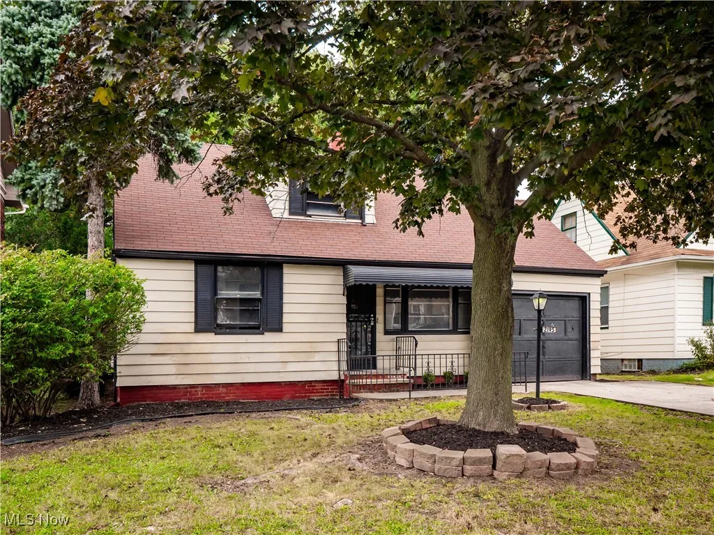 View of front facade featuring concrete driveway, a front yard, an attached garage, and roof with shingles