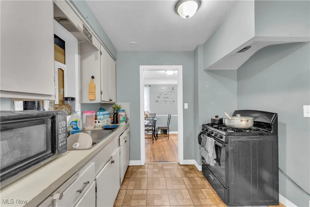 Kitchen with black appliances, light countertops, and white cabinetry