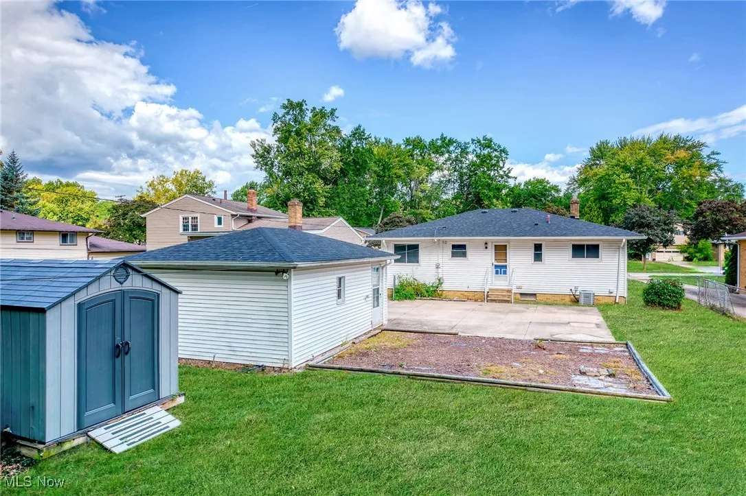 Back of property with a yard, a patio area, and a storage shed