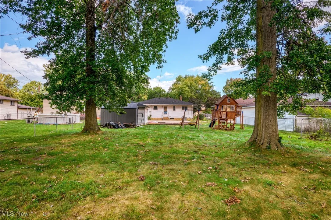Fenced backyard featuring an outbuilding