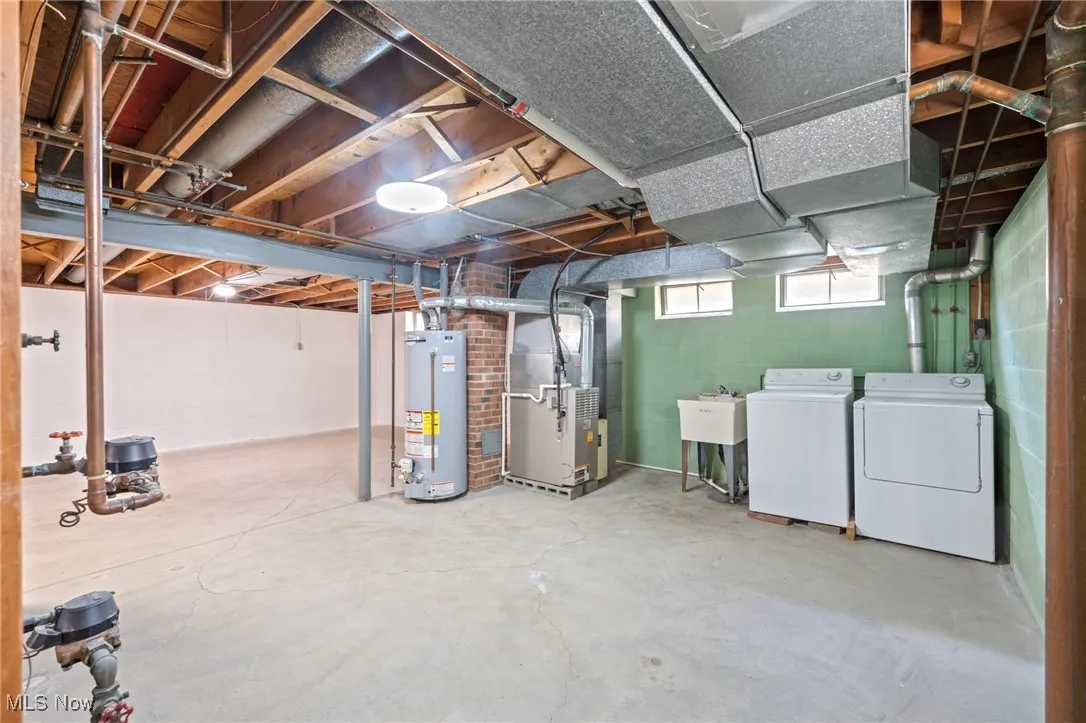 Below grade area featuring heating unit, water heater, and washing machine and clothes dryer
