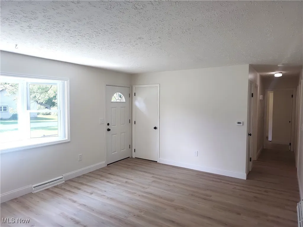 Entryway with light wood-style flooring and a textured ceiling
