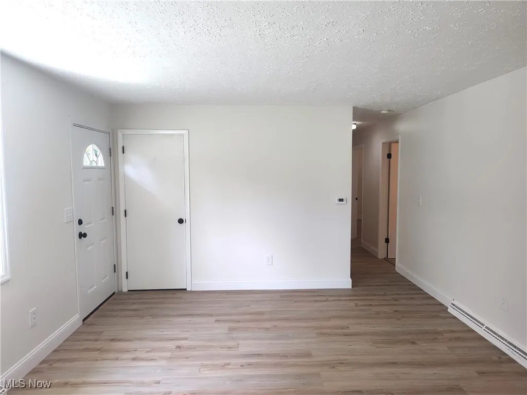 Entryway featuring light wood-style flooring, a textured ceiling, and baseboard heating