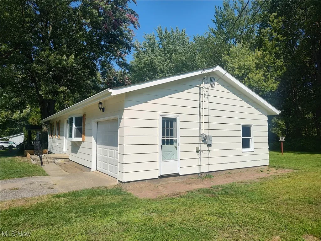 View of side of home with a yard and a garage