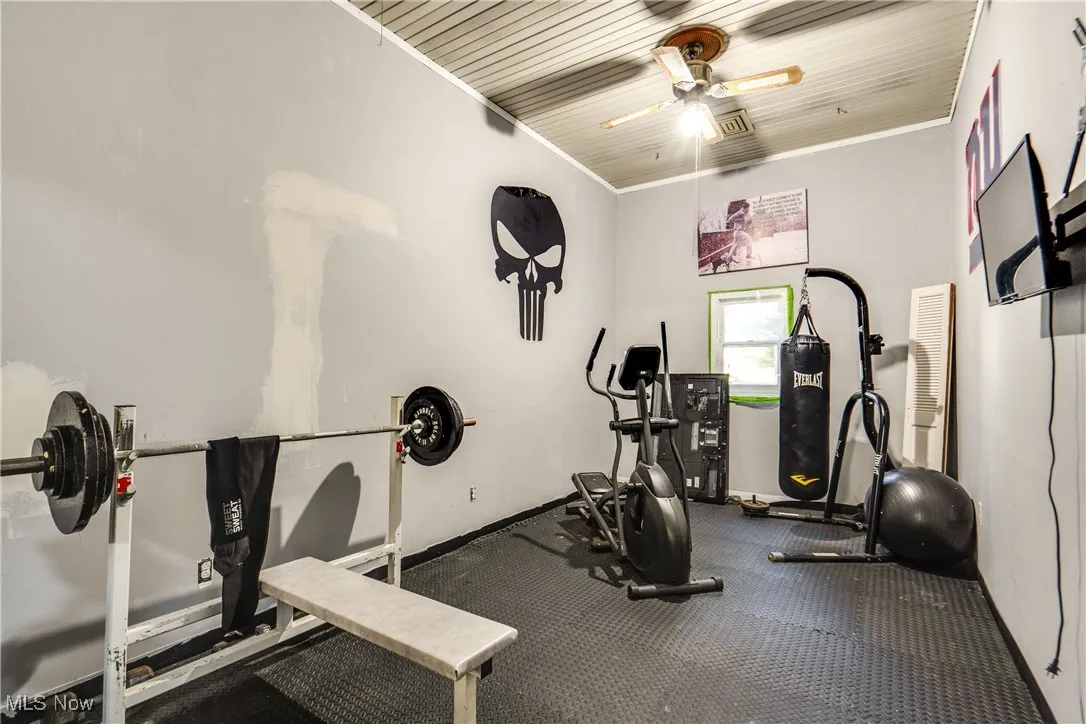 Workout area with ornamental molding and a ceiling fan