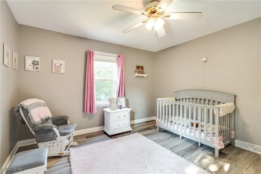 Bedroom featuring a nursery area, ceiling fan, and wood finished floors