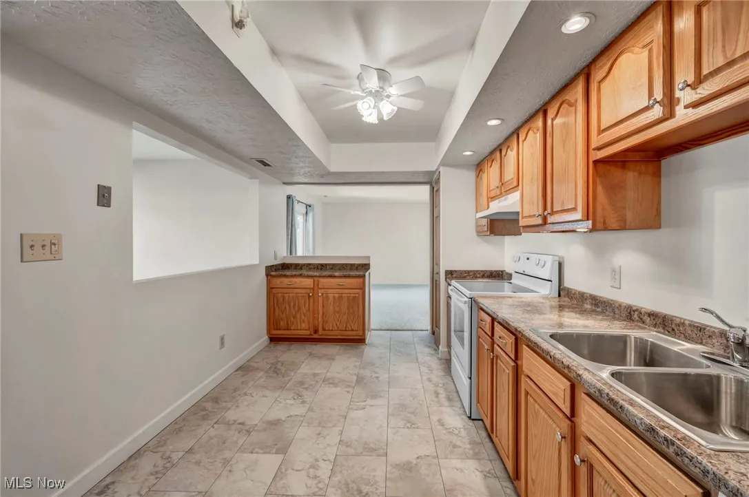Kitchen featuring white electric stove, recessed lighting, a ceiling fan, dark countertops, and brown cabinets