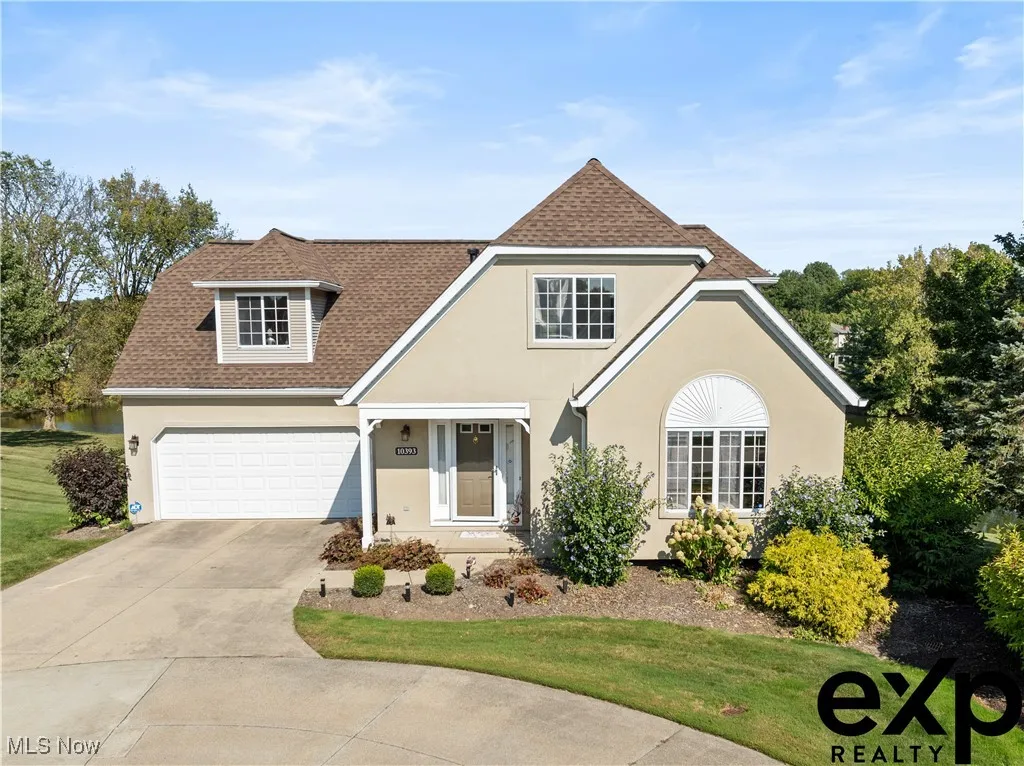 Traditional-style house with roof with shingles, driveway, stucco siding, and a front yard