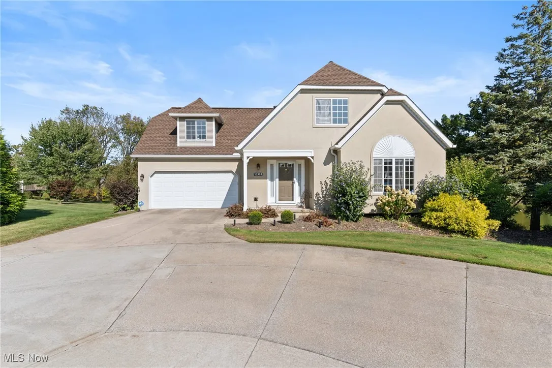 Traditional home with concrete driveway, stucco siding, a front yard, and roof with shingles