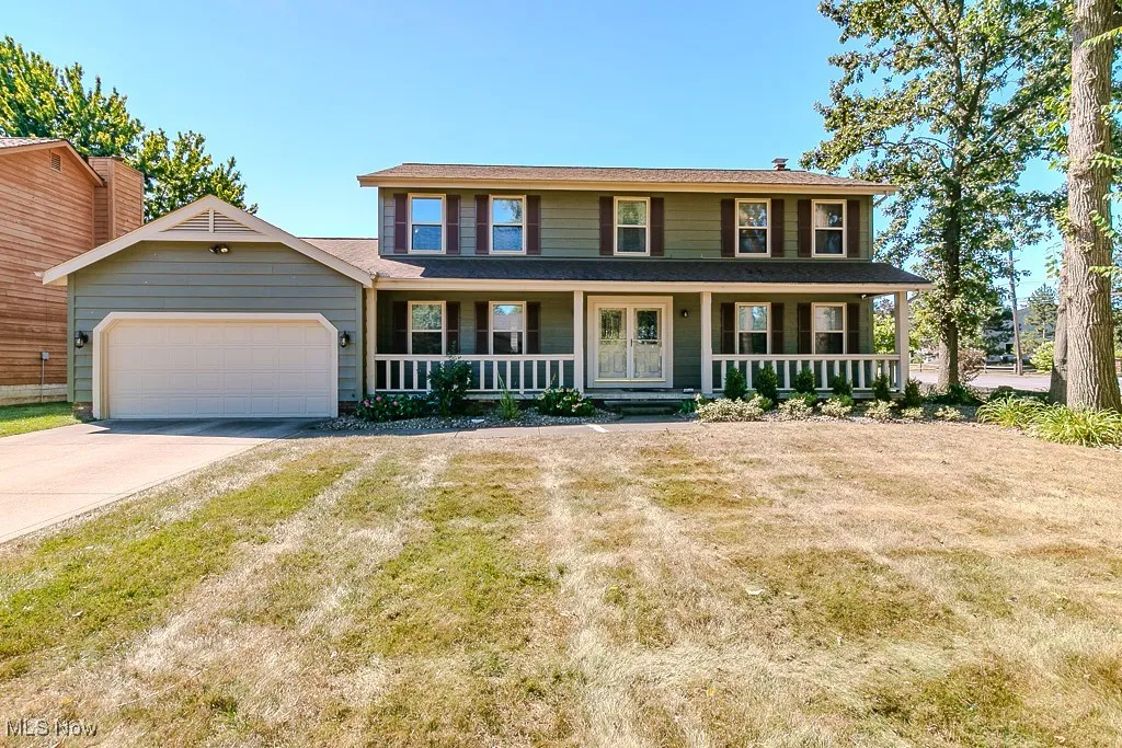 Colonial-style house with a front porch, an attached garage, and concrete driveway.